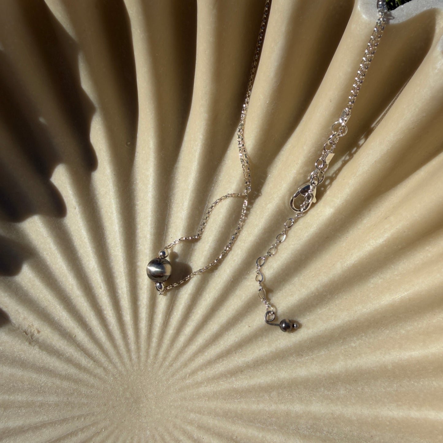 Necklace with a pendant on a textured beige surface