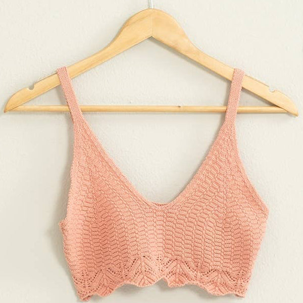 Pink crochet top on a wooden hanger against a light background