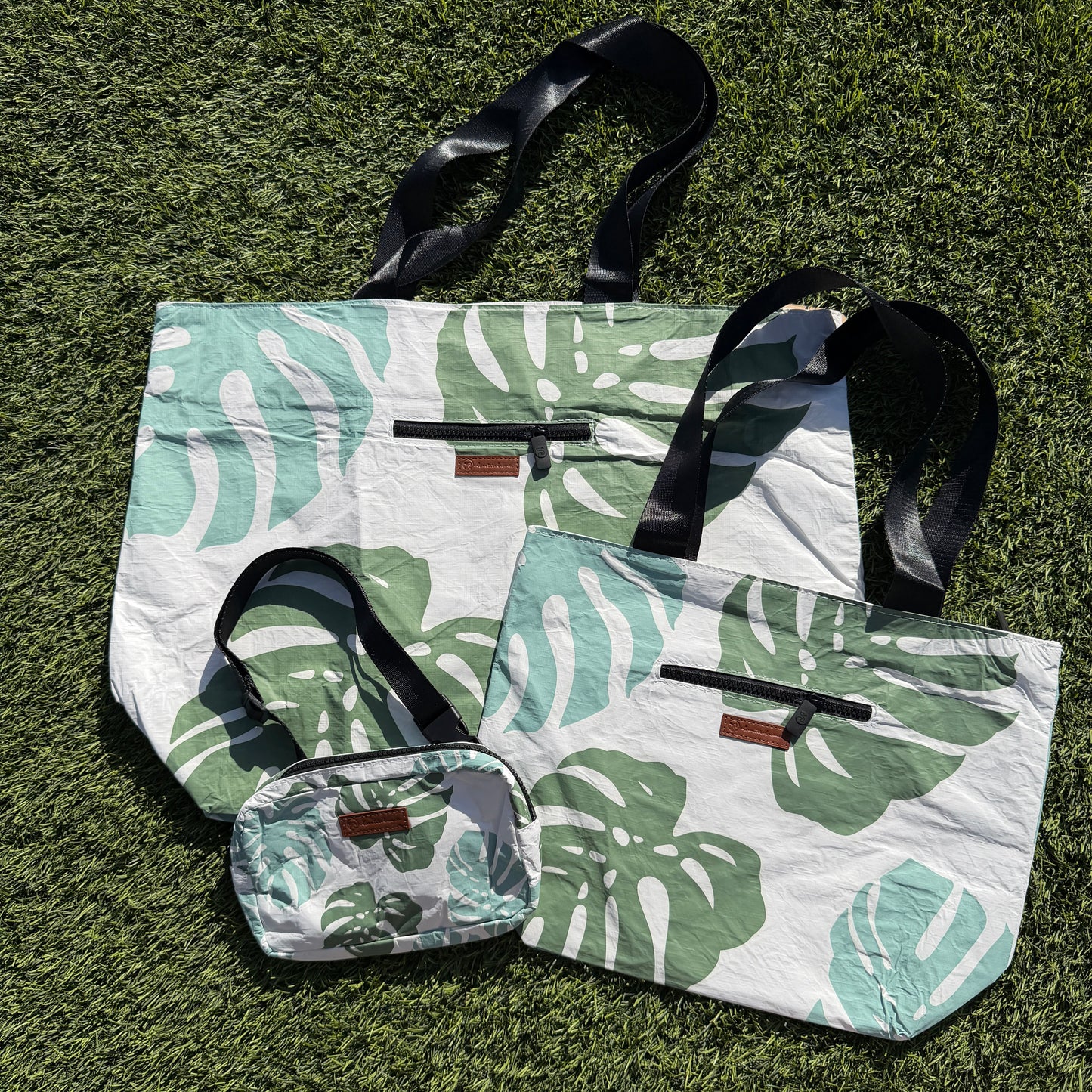 Set of tote bags with leaf pattern on a grass background
