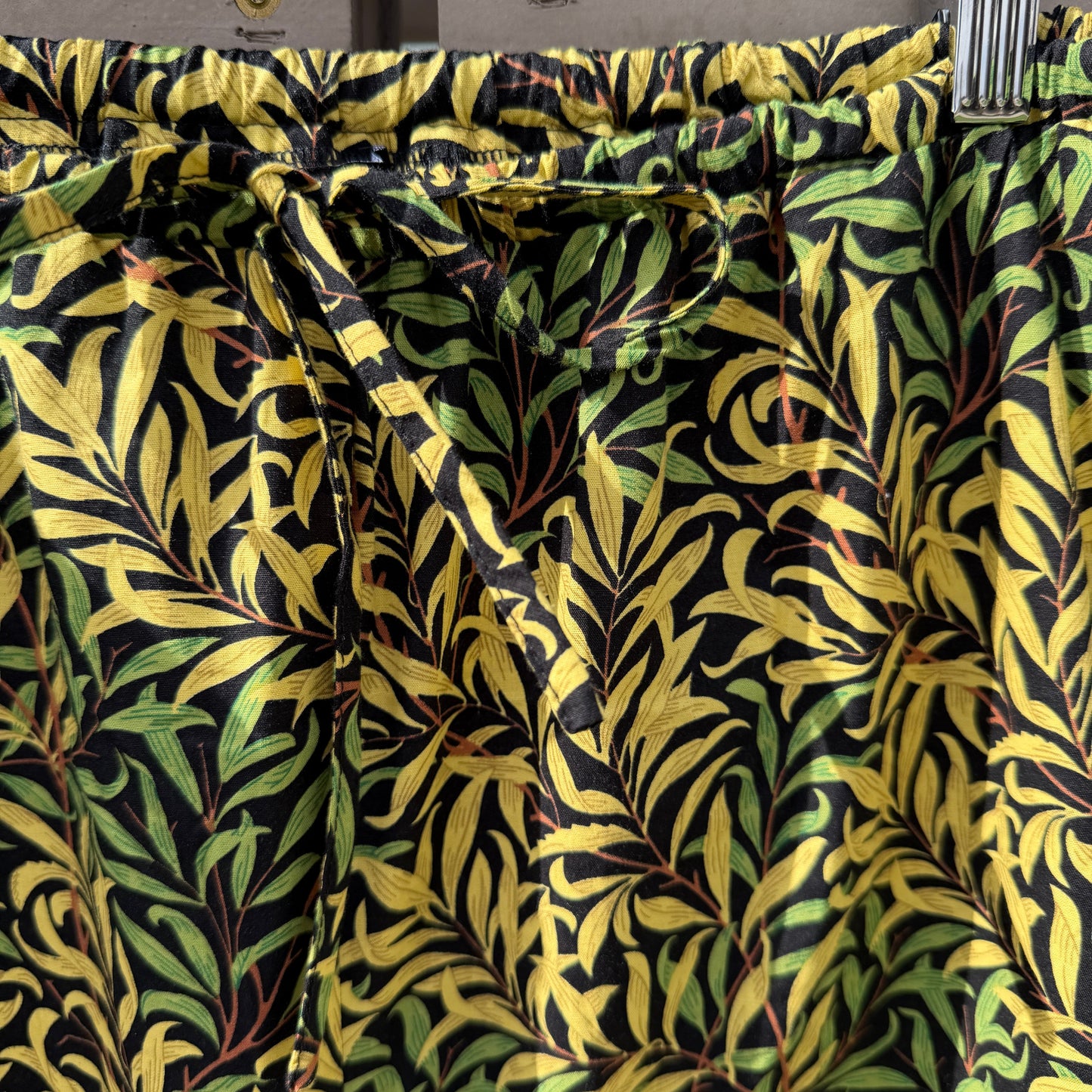 Fabric with a leaf pattern in green and black on a metal rod.