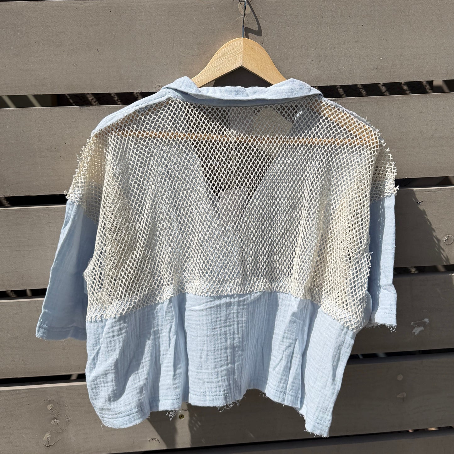 Light blue shirt on a wooden hanger against a wooden wall