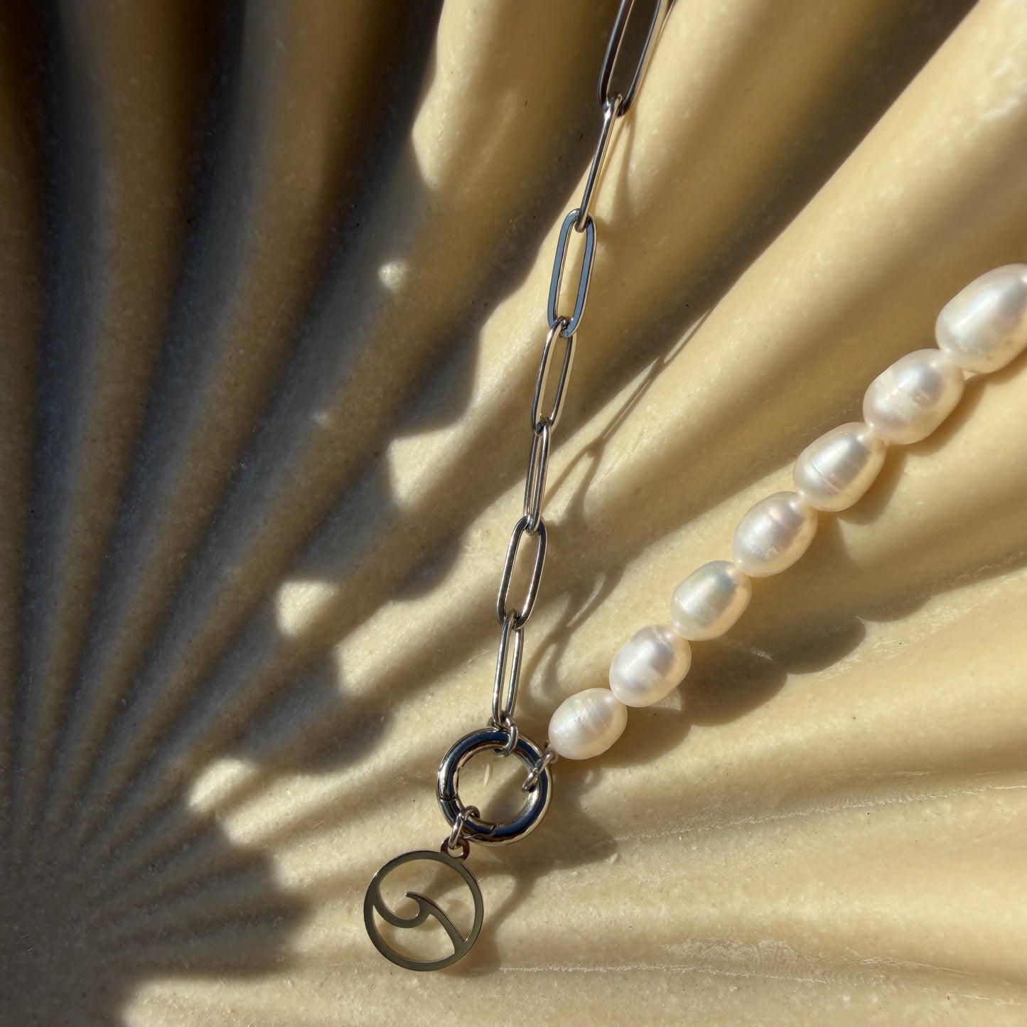 Pearl necklace with silver clasp on a textured beige surface