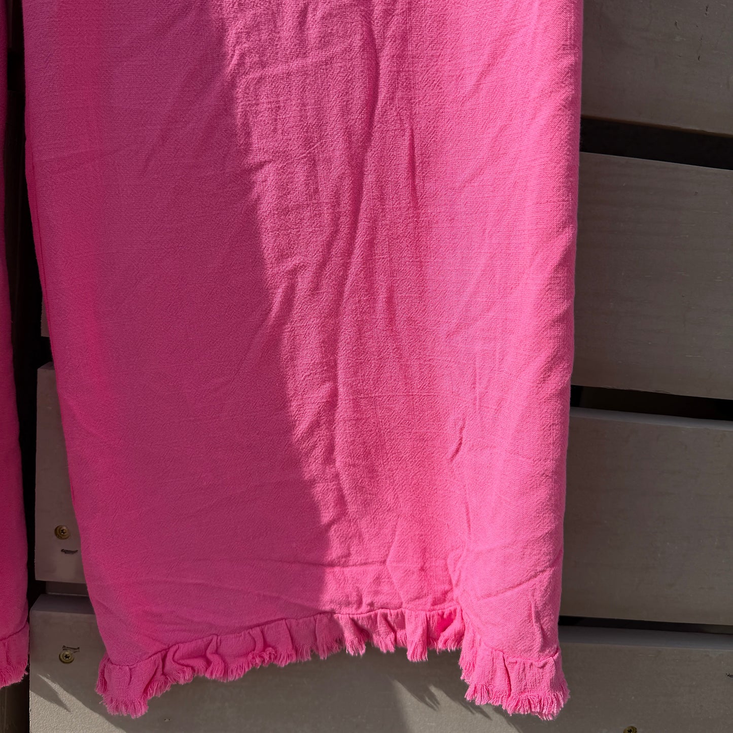 Pink fabric with ruffled edges on a wooden surface