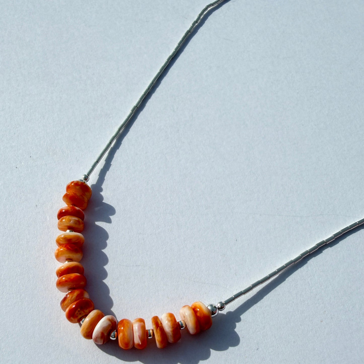 Necklace with orange beads on a light gray background