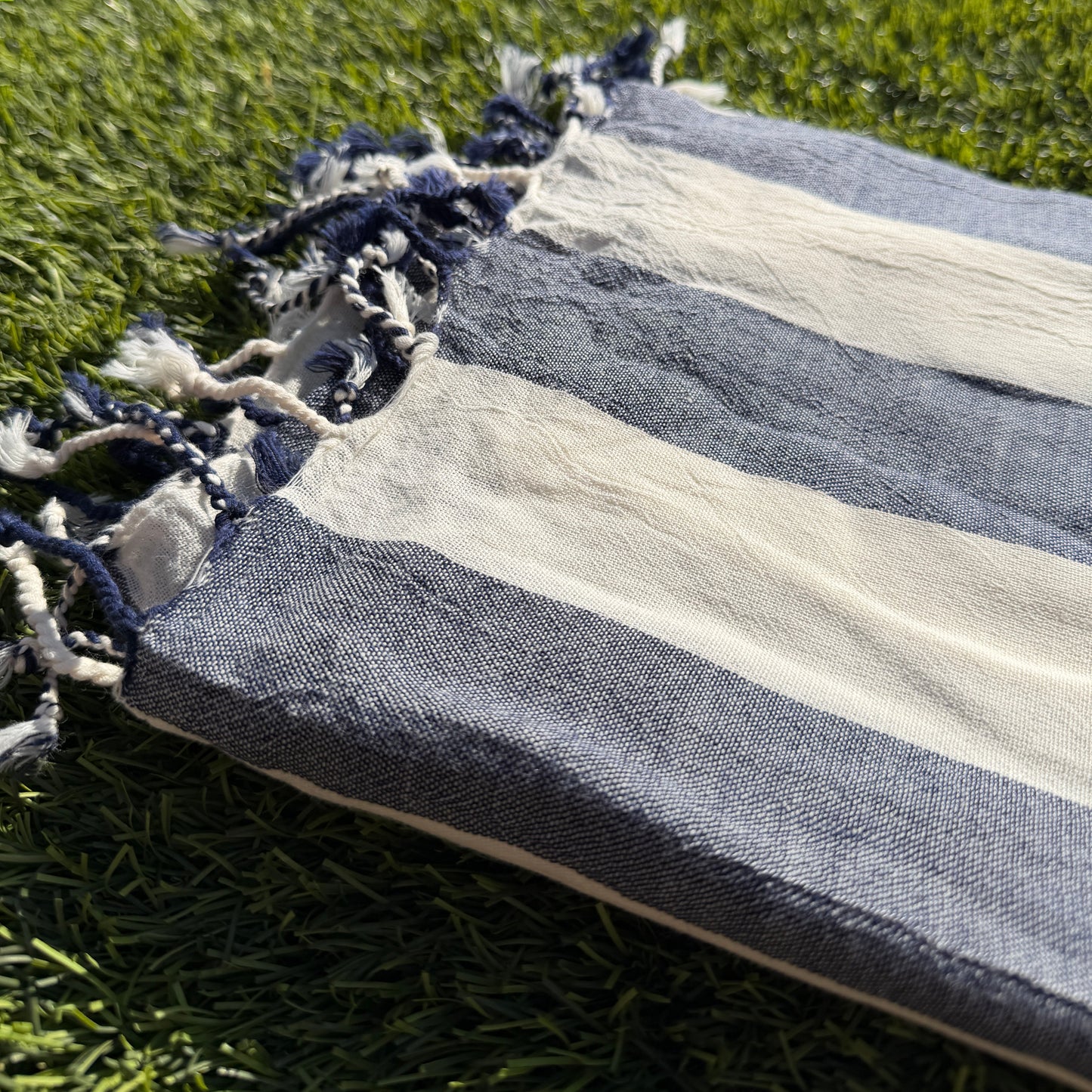 Striped towel with tassels on a grassy background