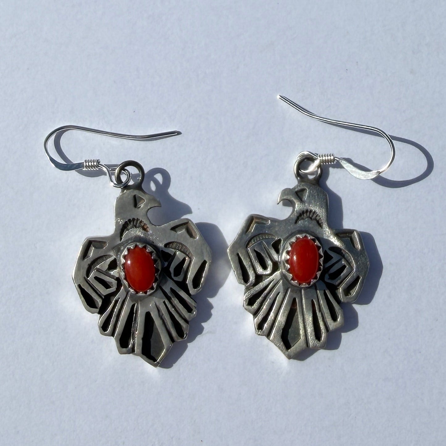 Pair of silver earrings with red stones on a light gray background