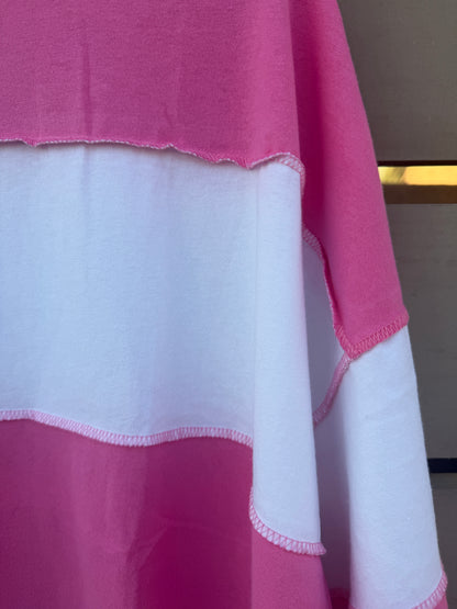 A close-up of a pink and white color-blocked fabric garment, showing the raw, scalloped edges of the material.