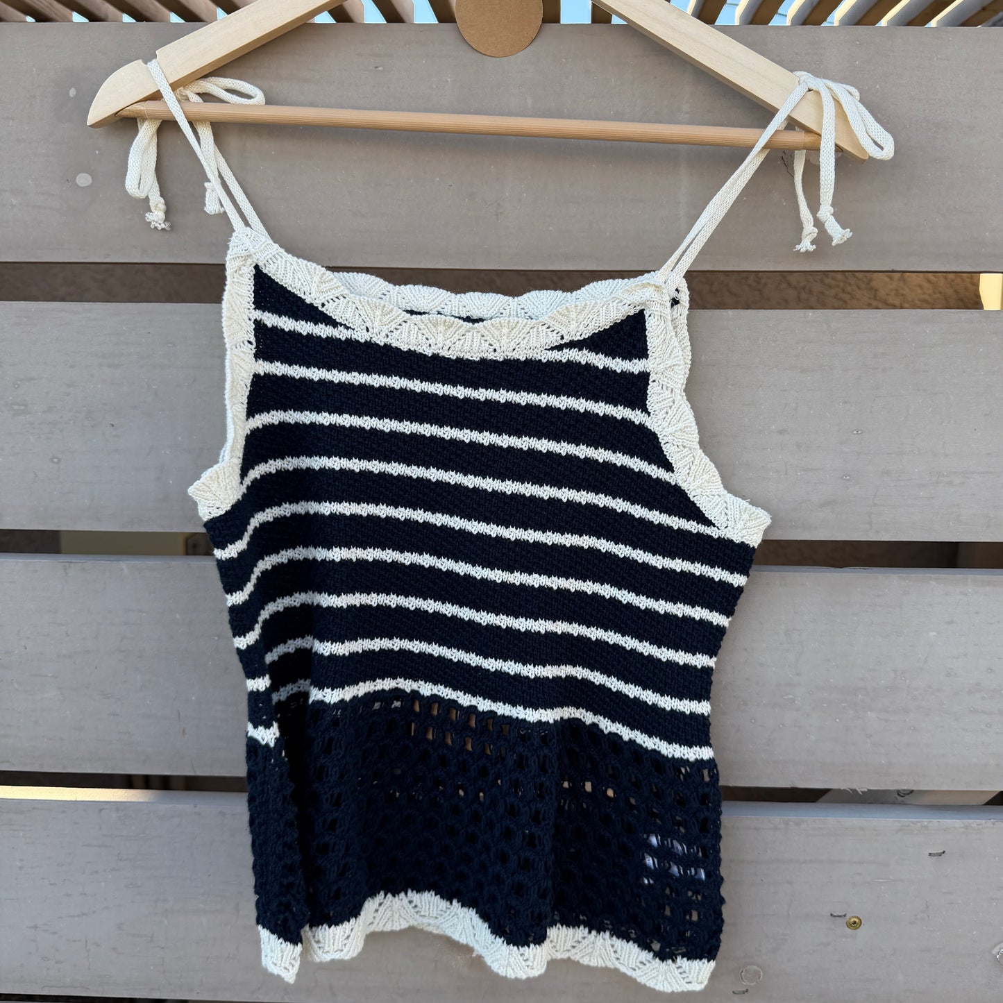 Black and white striped tank on a hanger against a wooden panel background