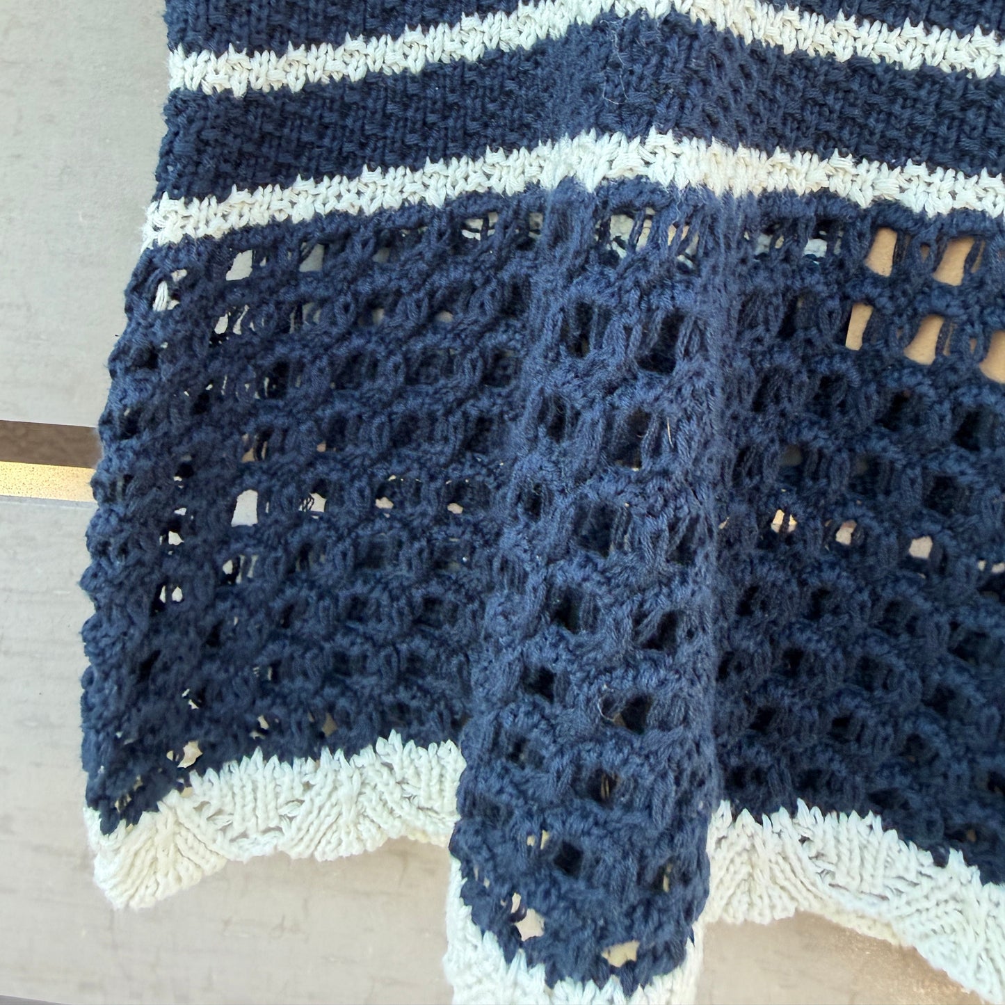 Blue and white crocheted tank on a wooden surface