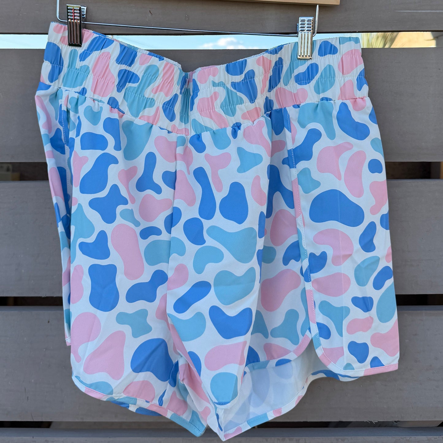 Colorful patterned shorts hanging on a wooden surface with a slatted background.