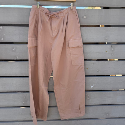 Beige cargo pants hanging on a wooden fence