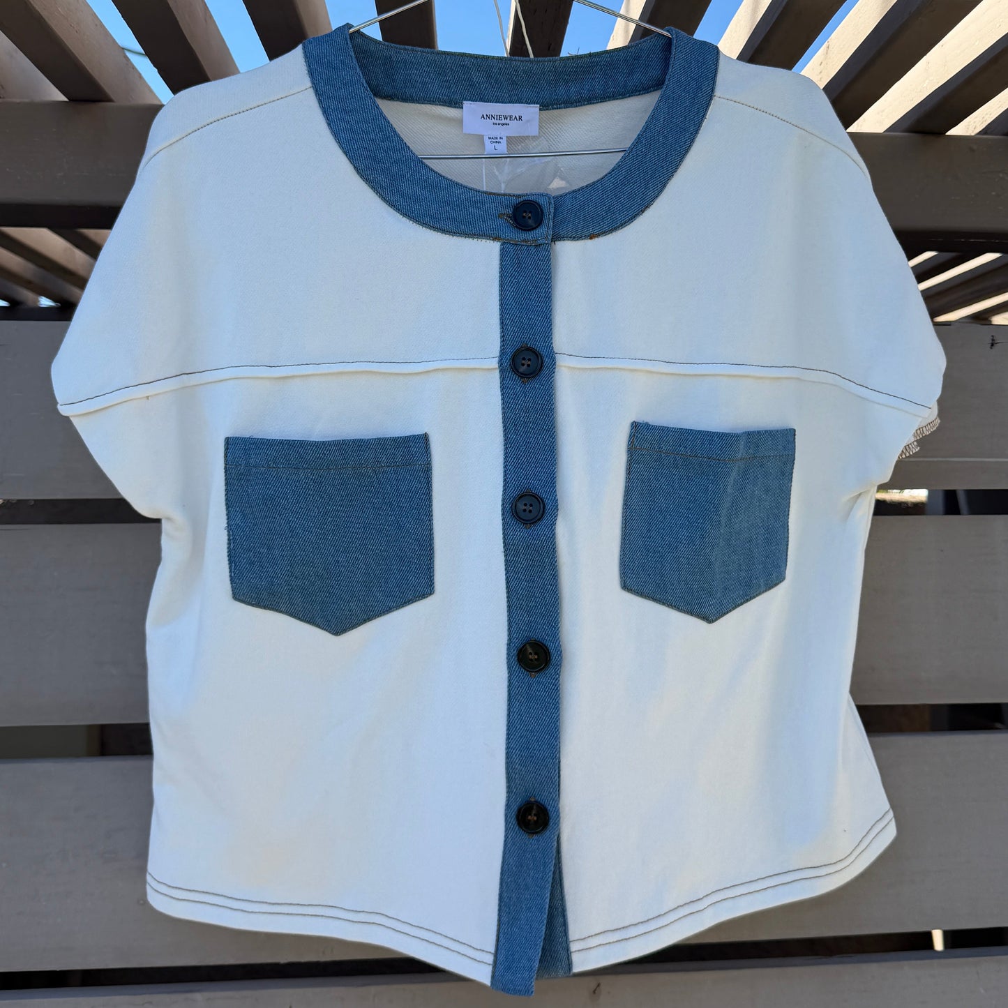 White and blue shirt on a wooden fence against a blue sky.