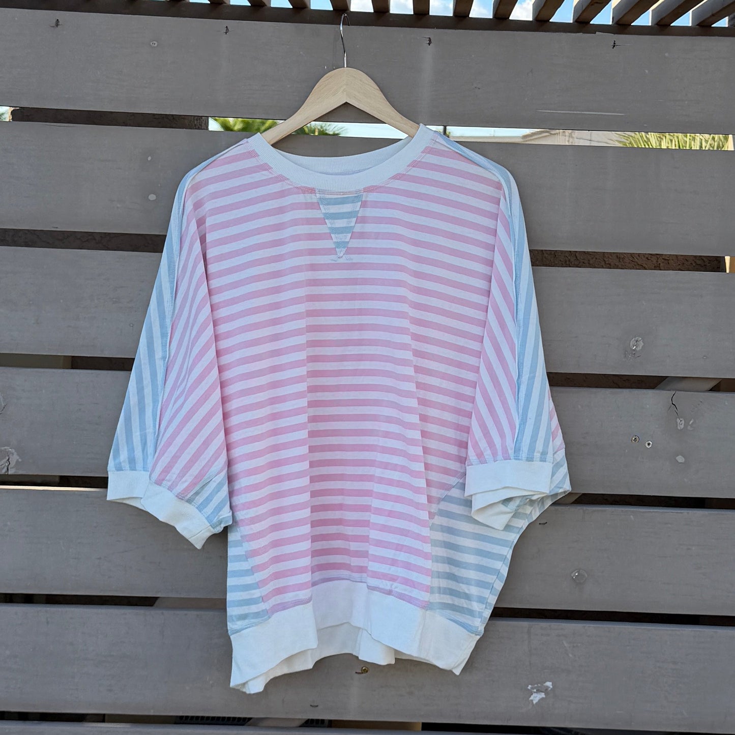 Pink and white striped shirt on a wooden deck with blue sky in the background