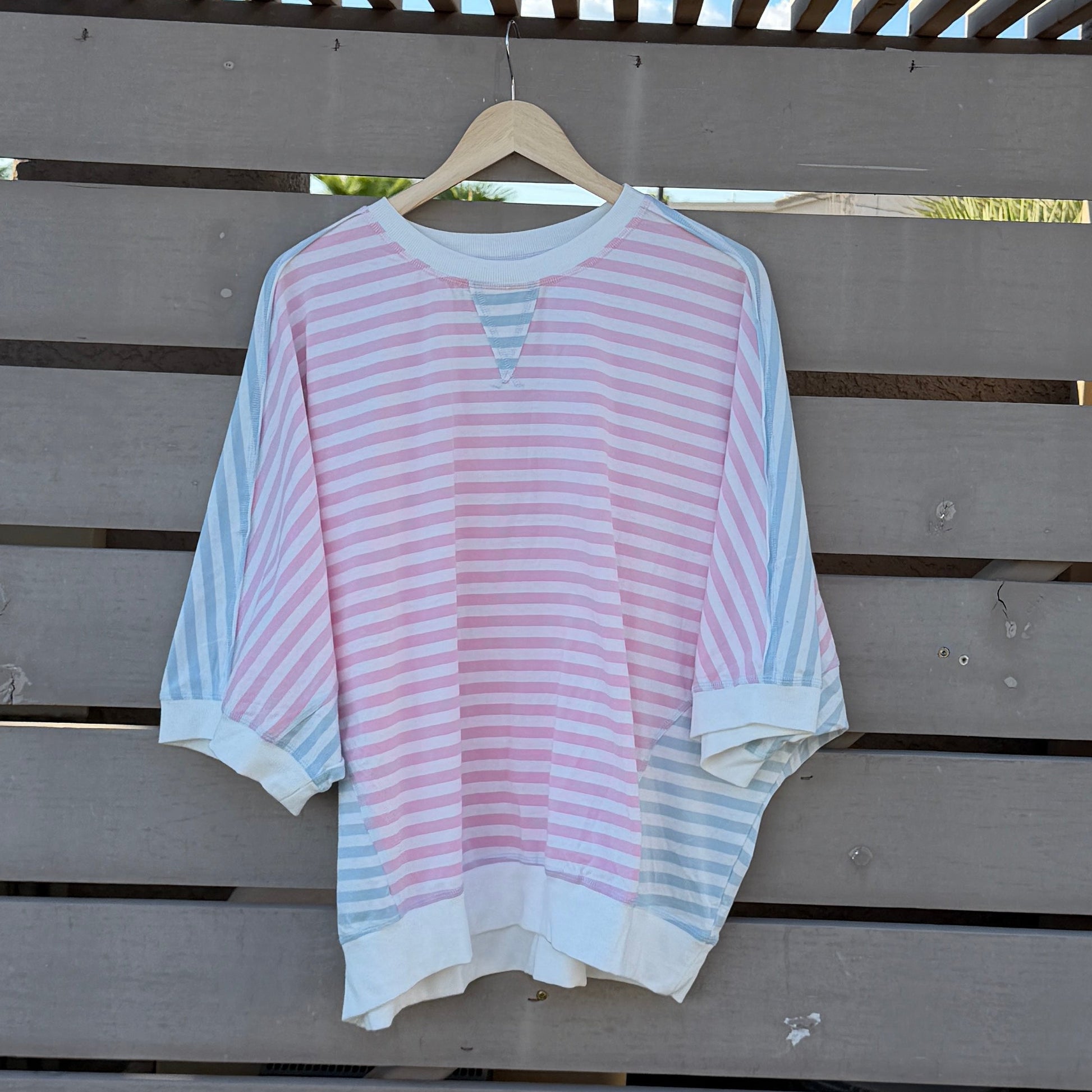 Pink and white striped shirt on a wooden deck with blue sky in the background
