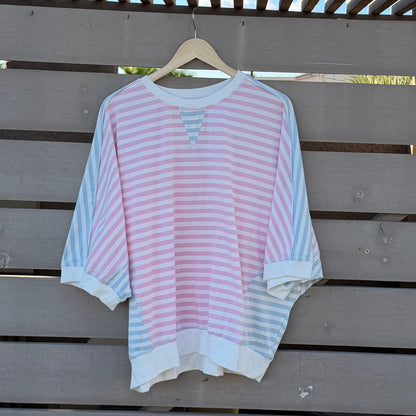 Pink and white striped shirt on a wooden deck with blue sky in the background