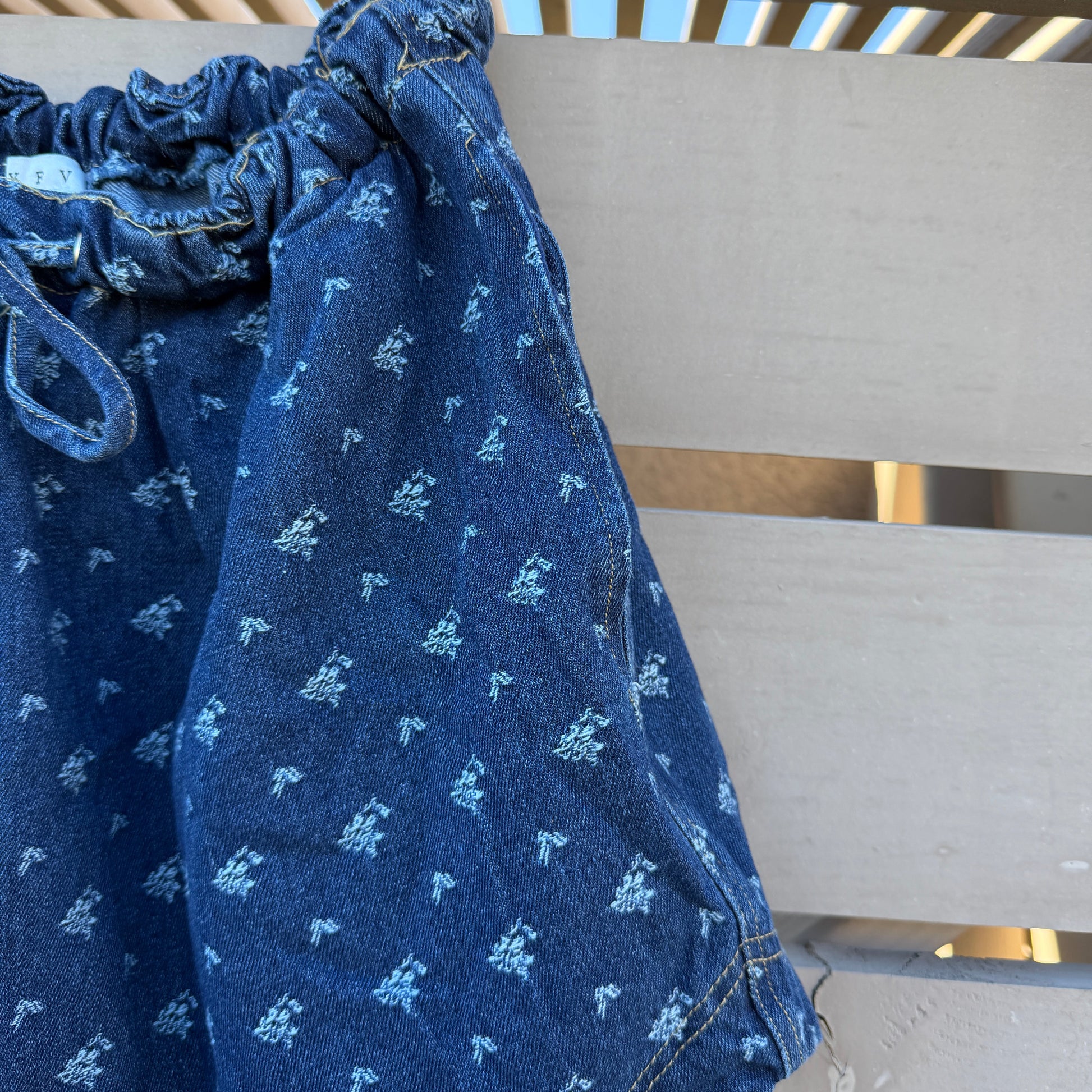 Blue patterned pants hanging on a metal rack.