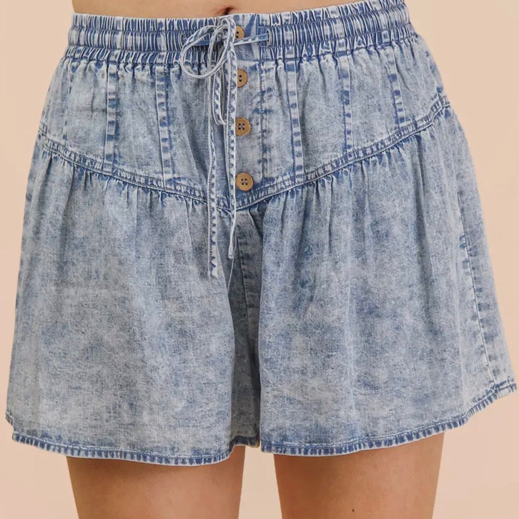 Denim shorts with button details on a beige background