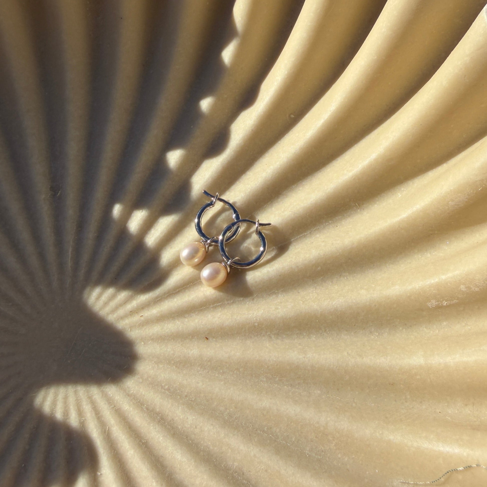 earrings in bowl with a scalloped edge on grass.