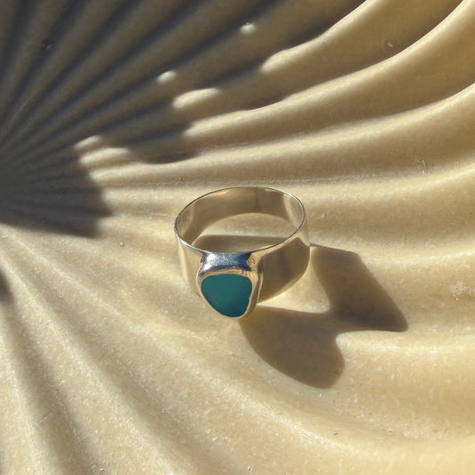 Silver ring with blue gemstone on a textured beige surface