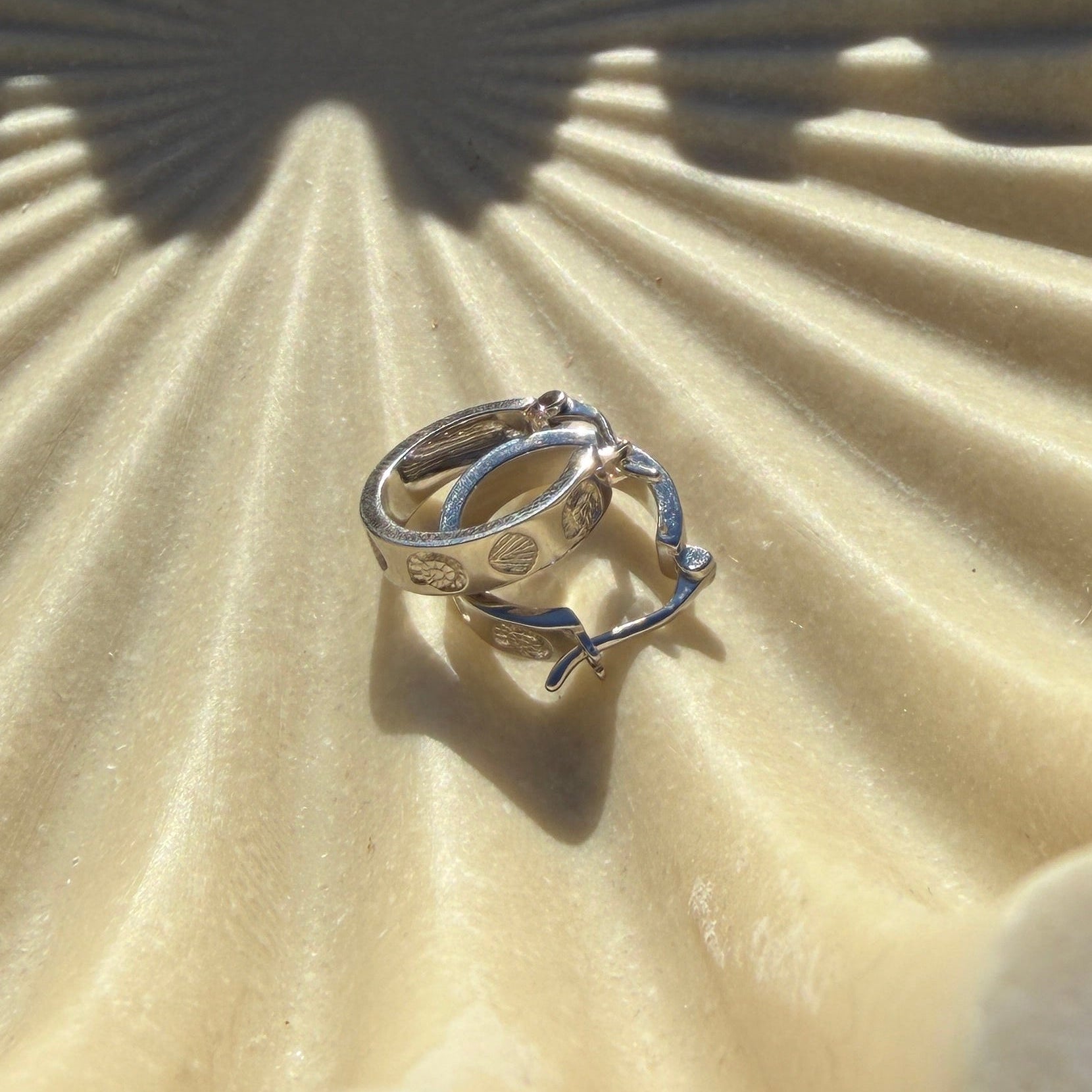 Silver earrings on a textured beige surface