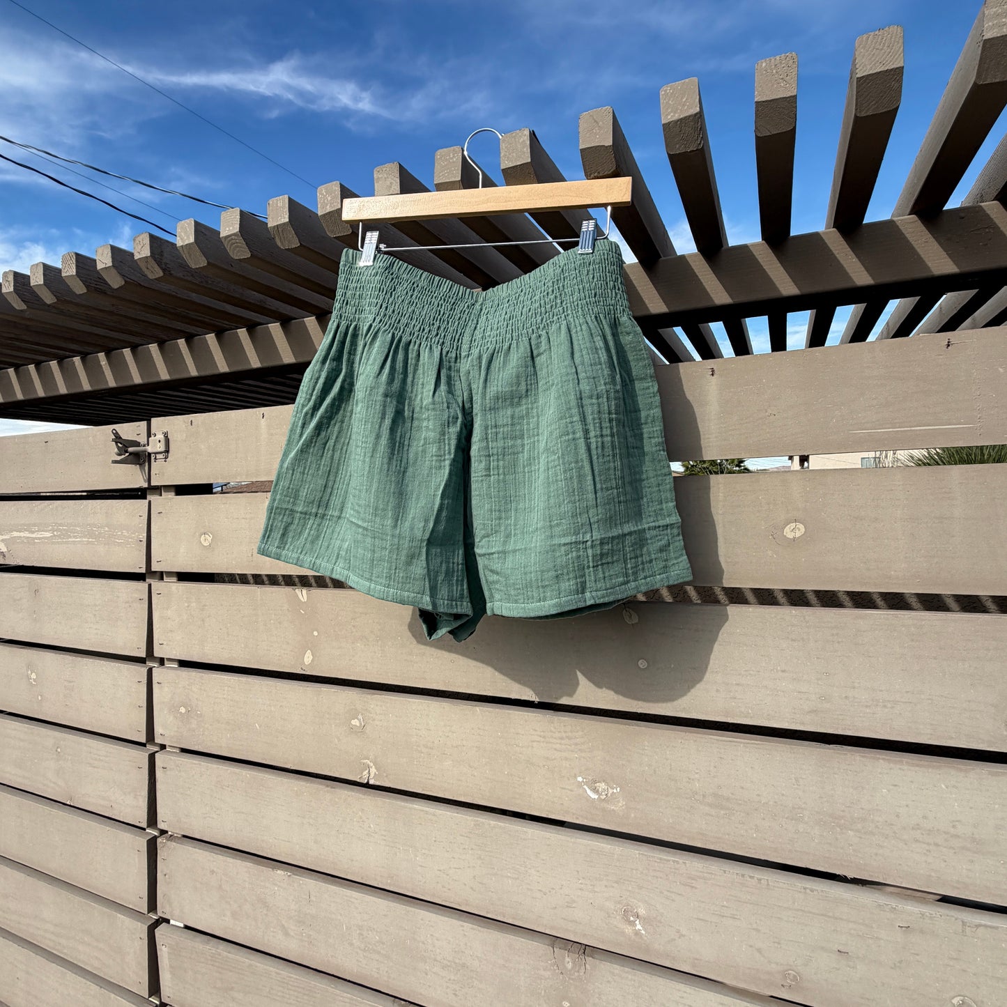 Green shirt hanging on a clothesline against a blue sky