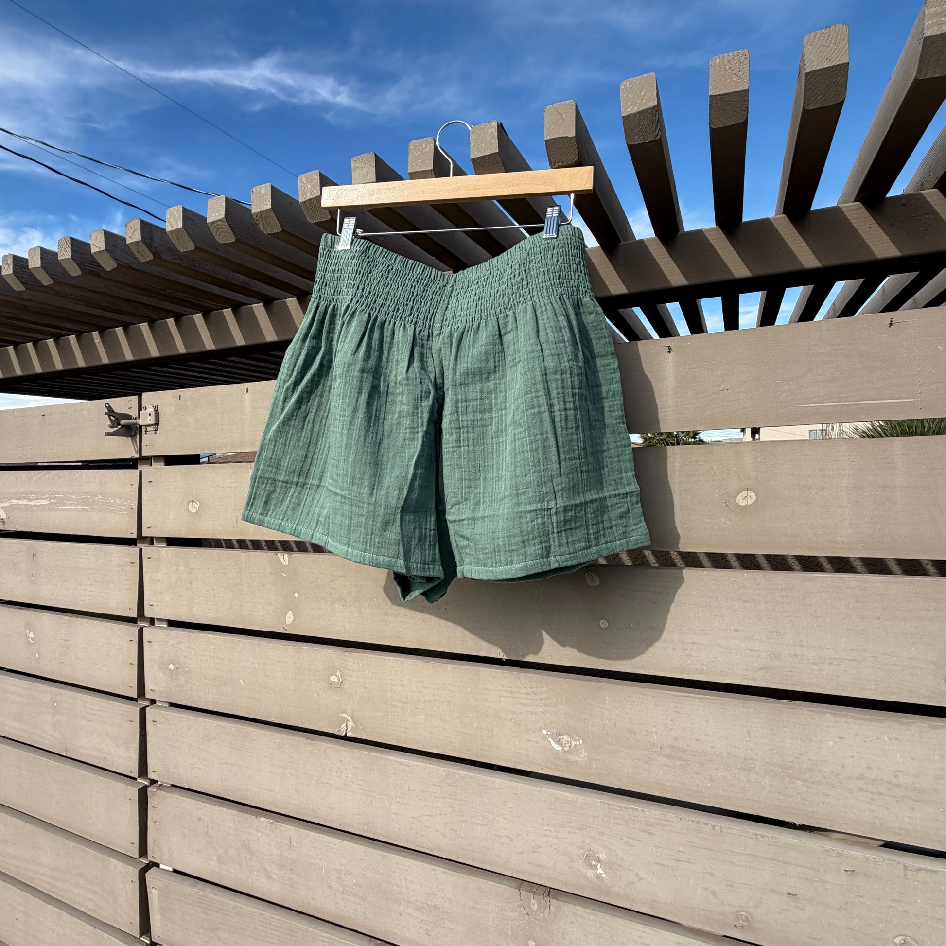 Green shirt hanging on a clothesline against a blue sky