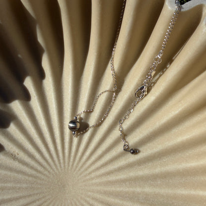 Necklace with a pendant on a textured beige surface