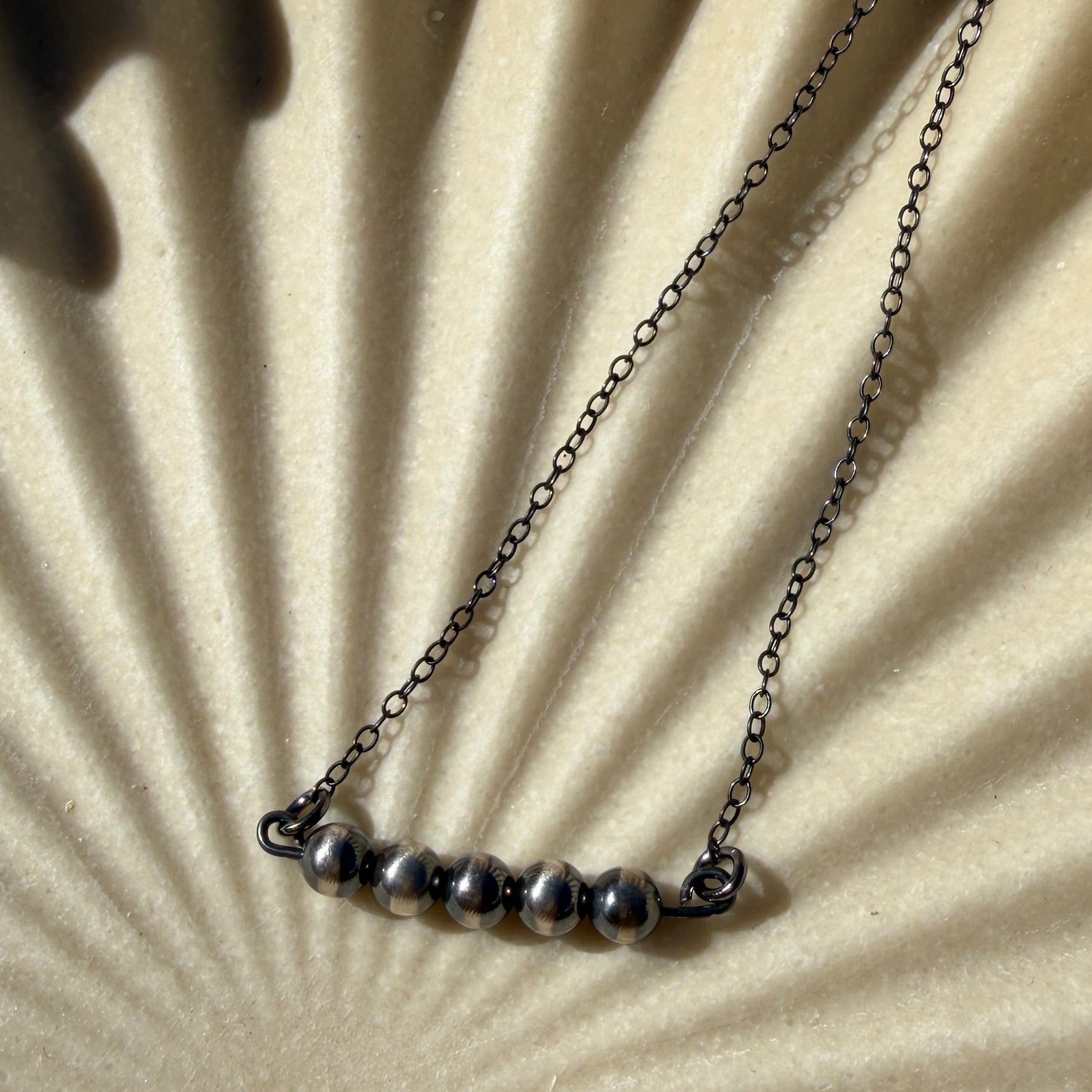 Necklace on a textured beige surface with a sunburst pattern