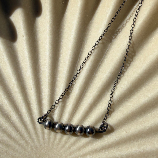 Necklace on a textured beige surface with a sunburst pattern