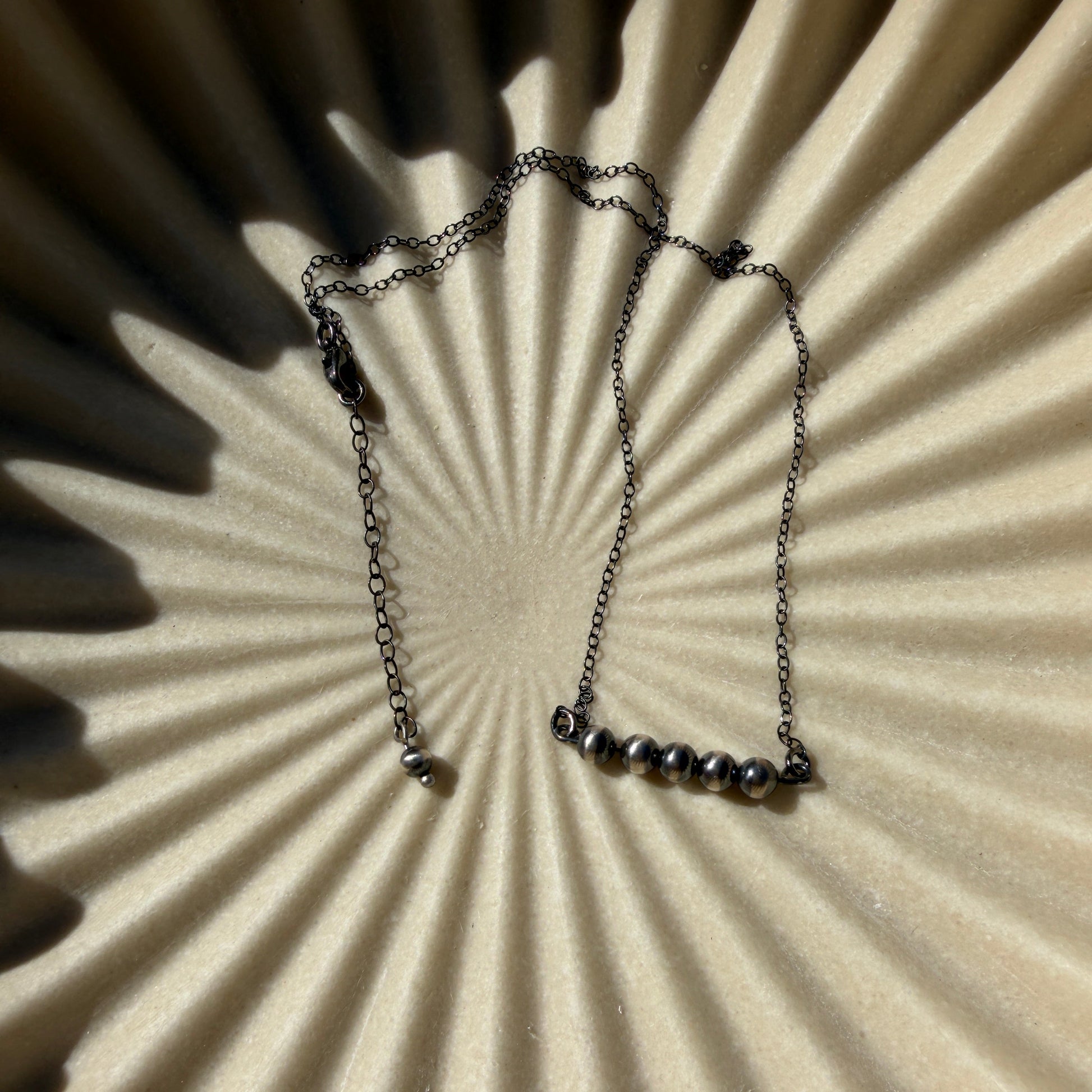 Necklace on a textured beige surface with shadows