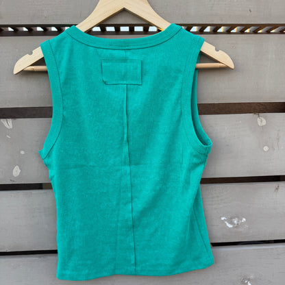 A sleeveless teal green top hanging on a wooden hanger against a gray wooden slat wall.
