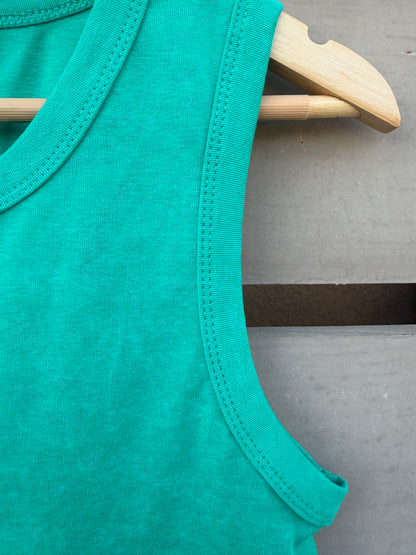 Close-up of a bright teal sleeveless top hanging on a light wood hanger against a gray wooden surface.