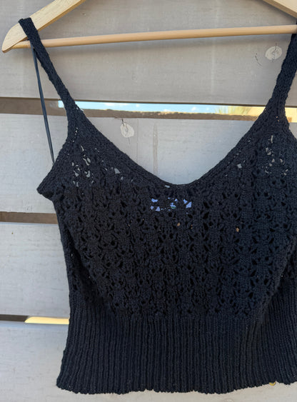 Black crochet top on a wooden hanger against a wooden background