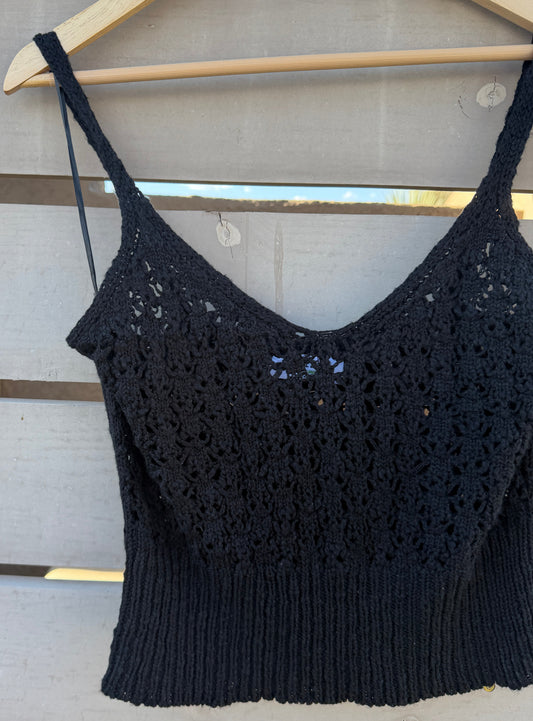 Black crochet top on a wooden hanger against a wooden background