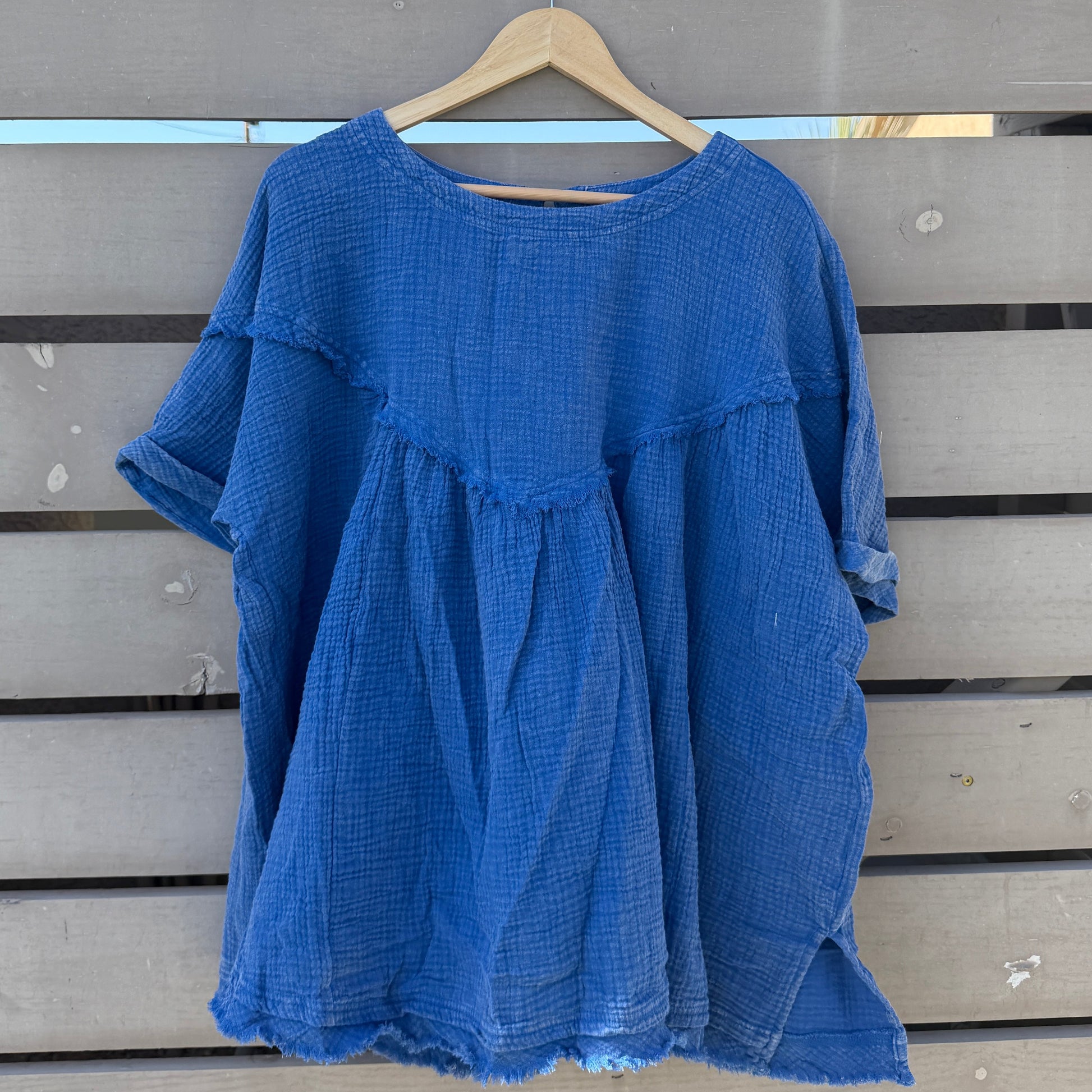 Blue shirt on a hanger against a wooden slat background