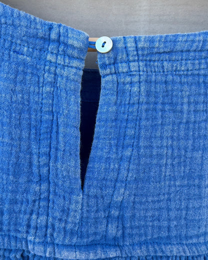 Close-up of a blue textured fabric with a button on a neutral background