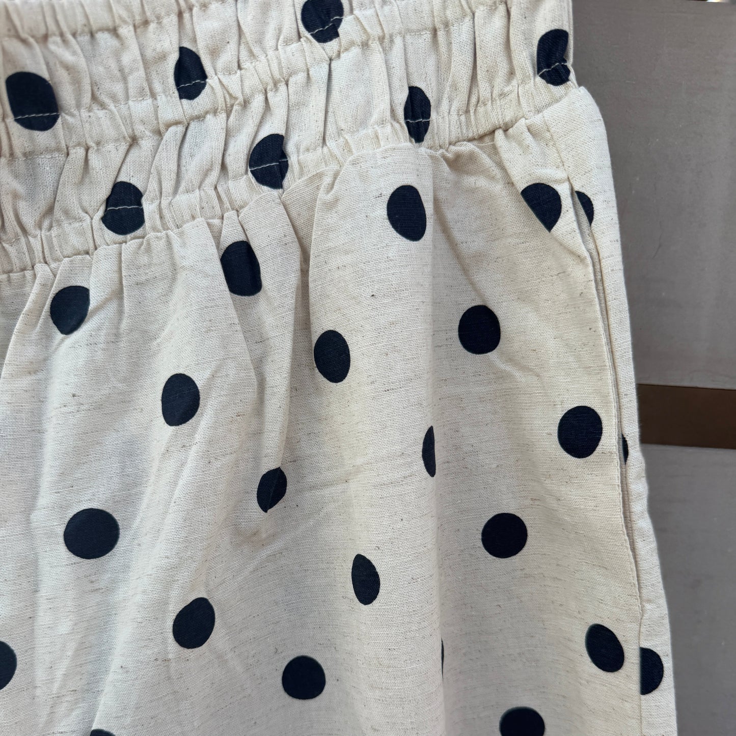 Close-up of a cream-colored fabric garment with a black polka dot pattern and an elastic waistband.