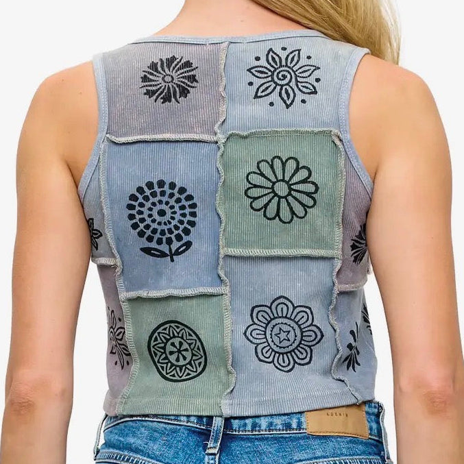 Person wearing a sleeveless denim top with patchwork design on a white background