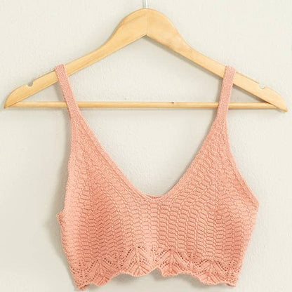 Pink crochet top on a wooden hanger against a light background