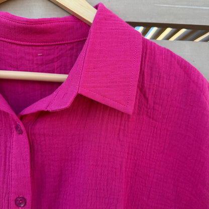 Close-up of a magenta shirt with a wooden object in the foreground