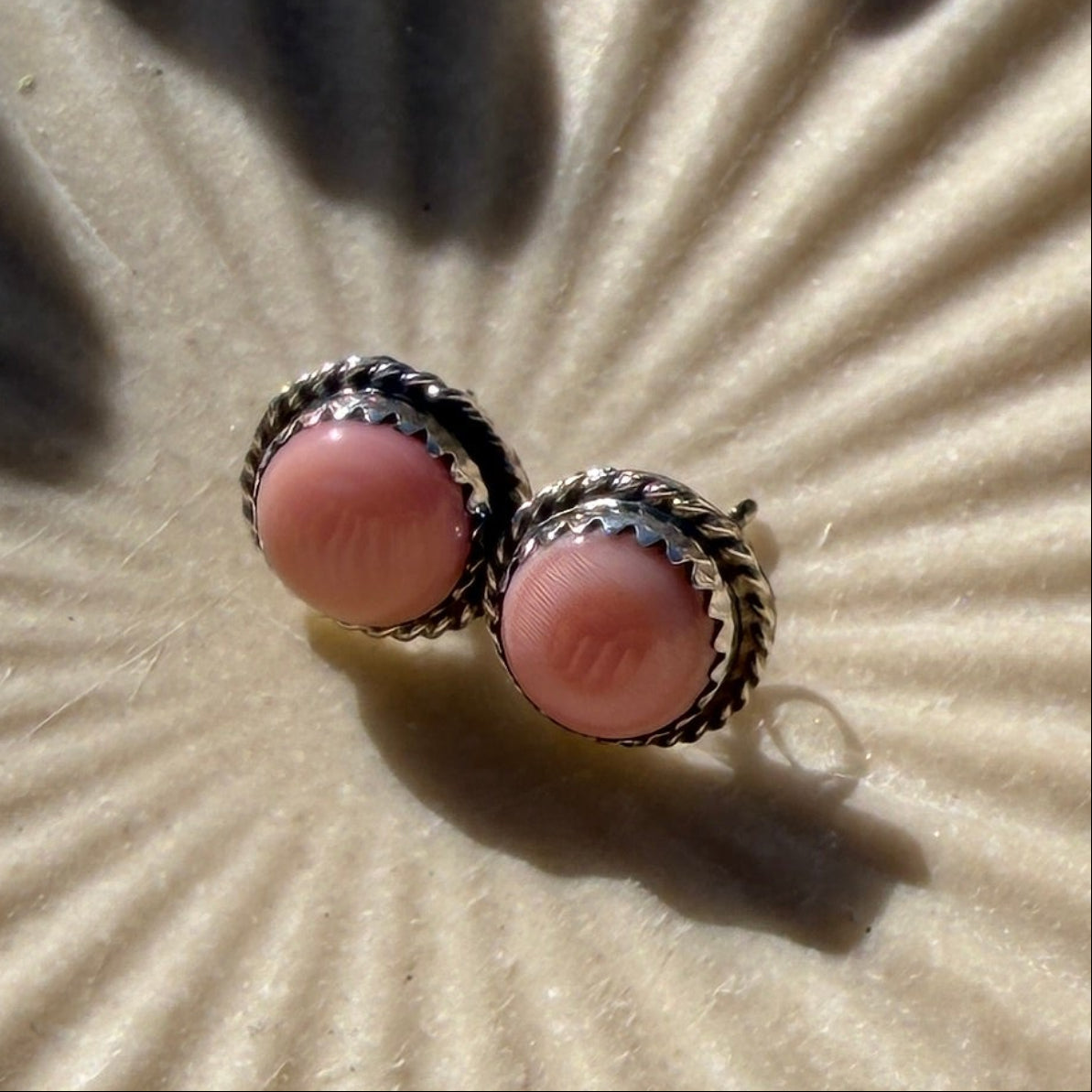 Pink conch studs on a textured surface