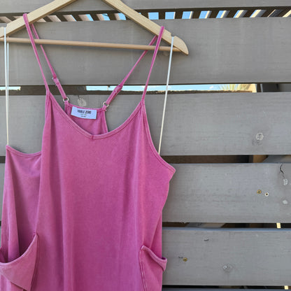 Pink jumpsuit on a hanger against a wooden panel background