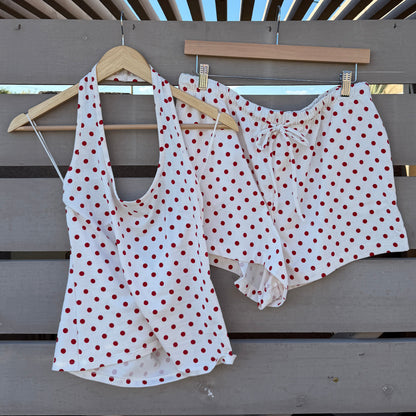 White polka dot top and shorts hanging on a wooden rack against a blue sky.