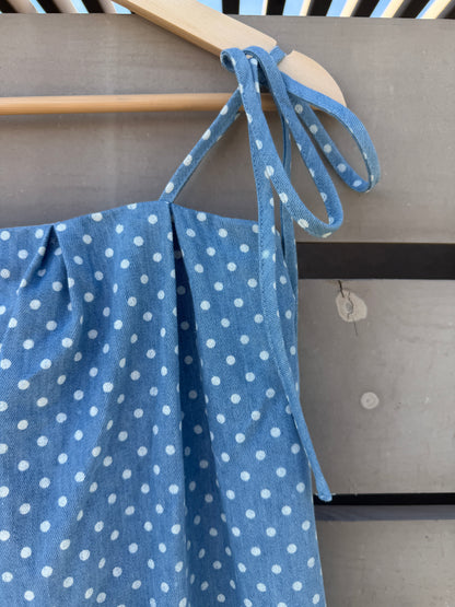 Blue polka dot fabric draped over a wooden frame against a neutral background