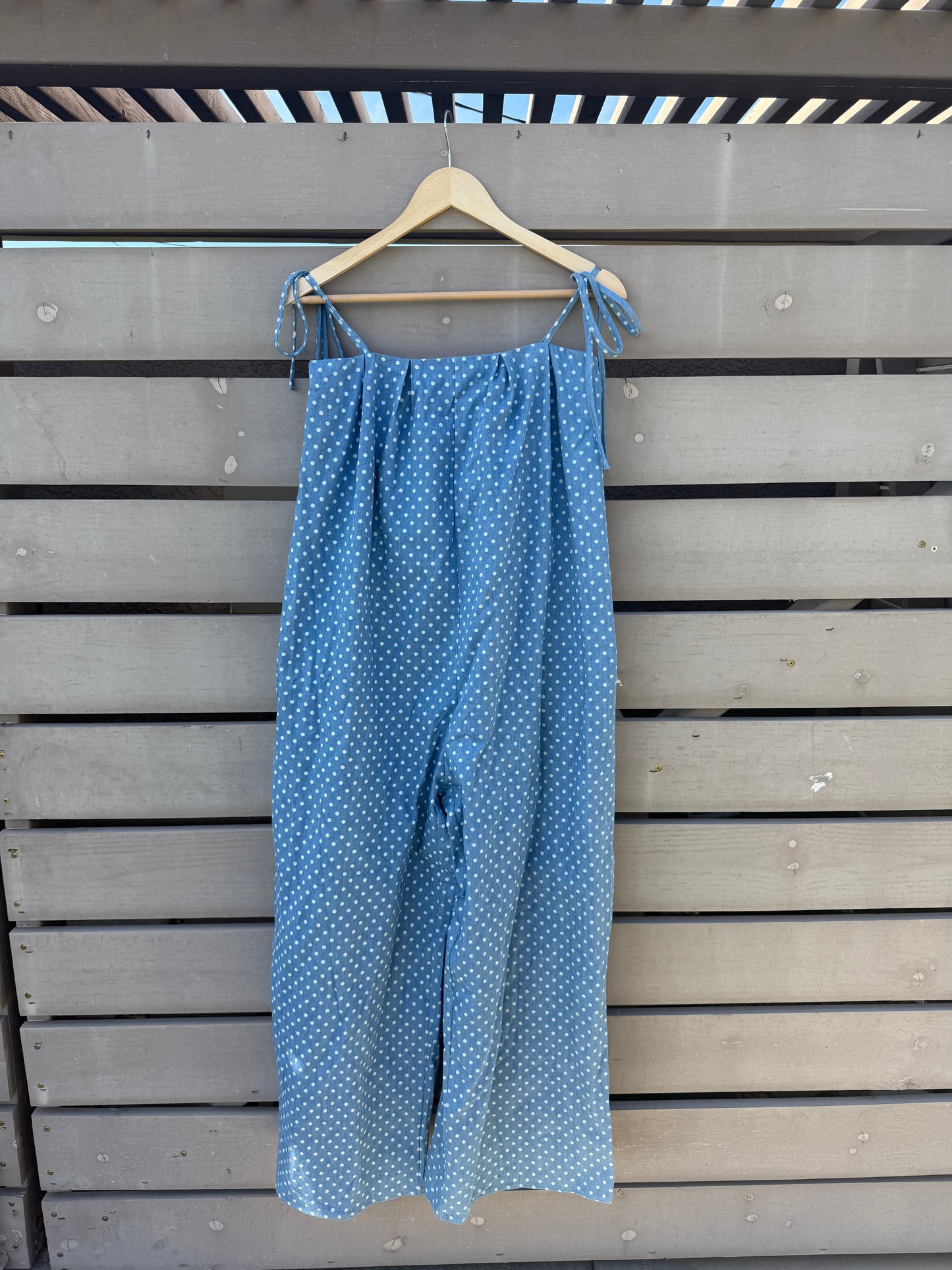 Blue polka dot fabric on a hanger against a wooden panel background