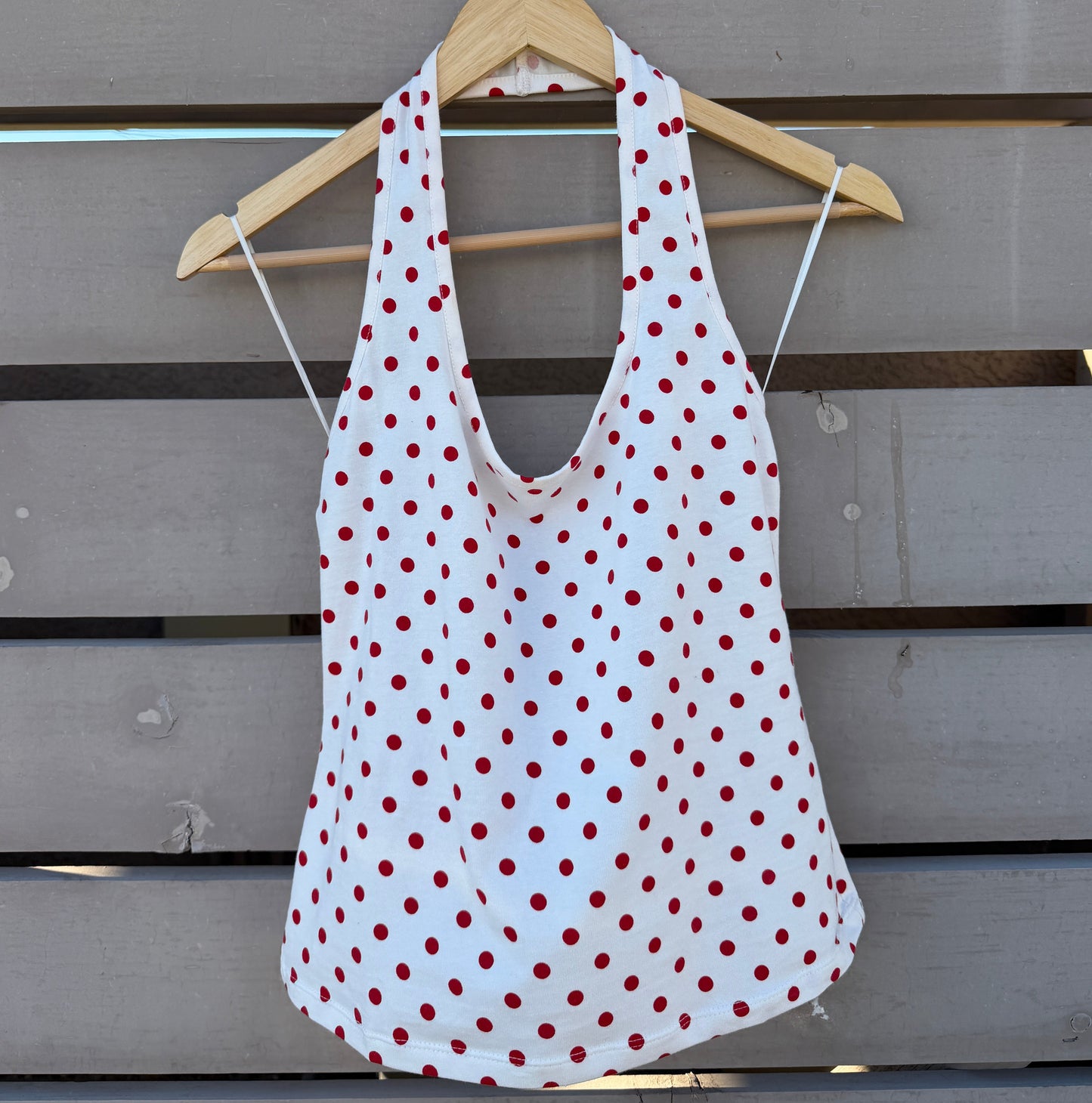 White tank top with red polka dots on a wooden background