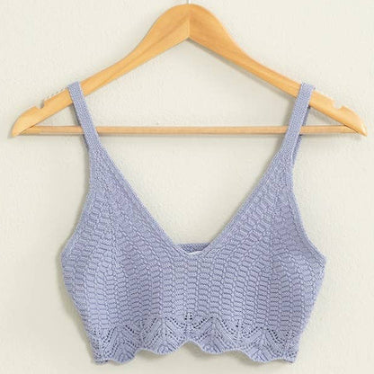Purple lace bralette on a wooden hanger against a beige background