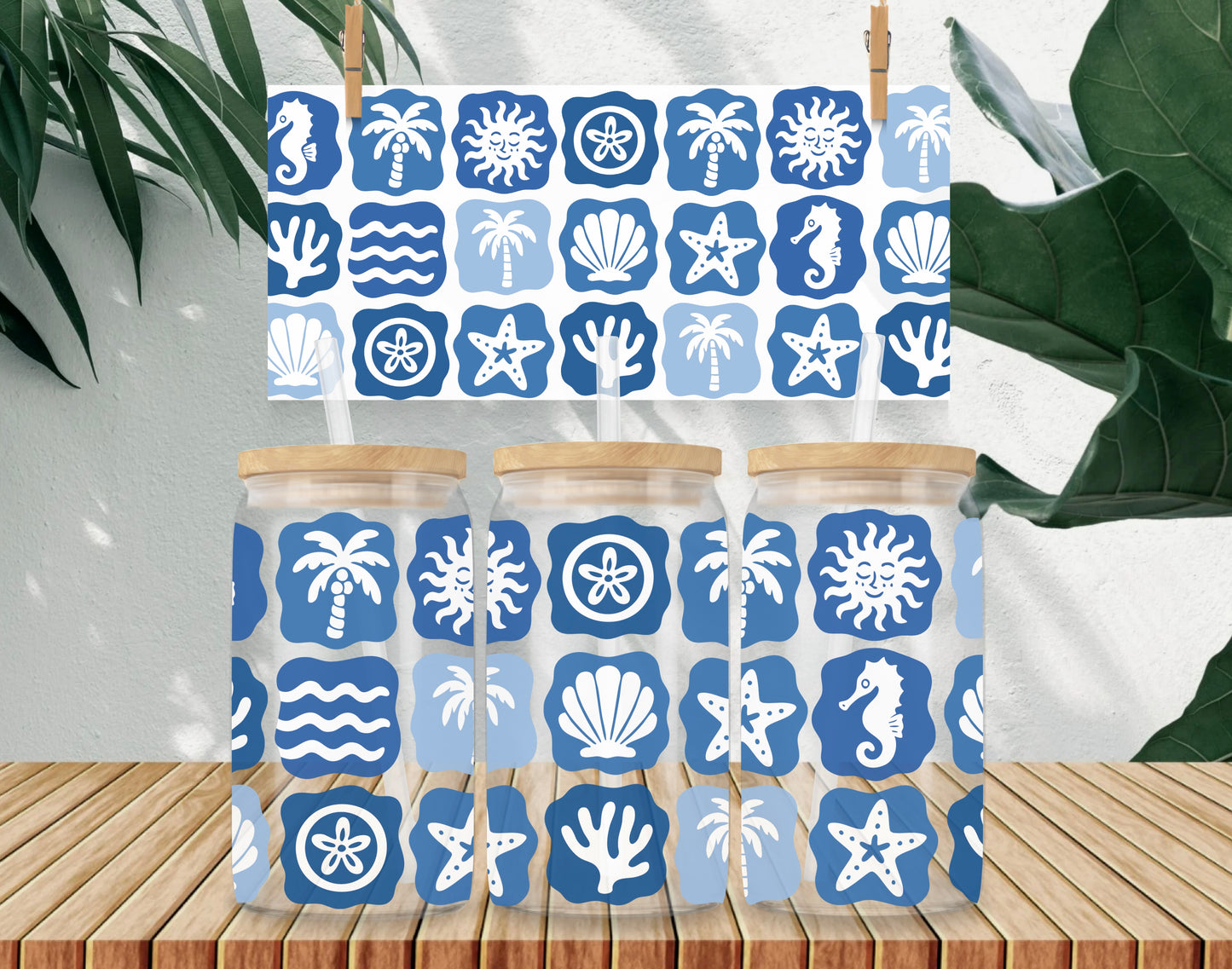 Towel with blue and white beach-themed pattern on a wooden surface with plants in the background