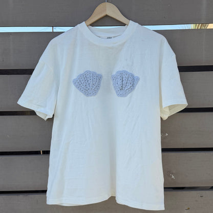 White t-shirt with blue shell patterns on a wooden background