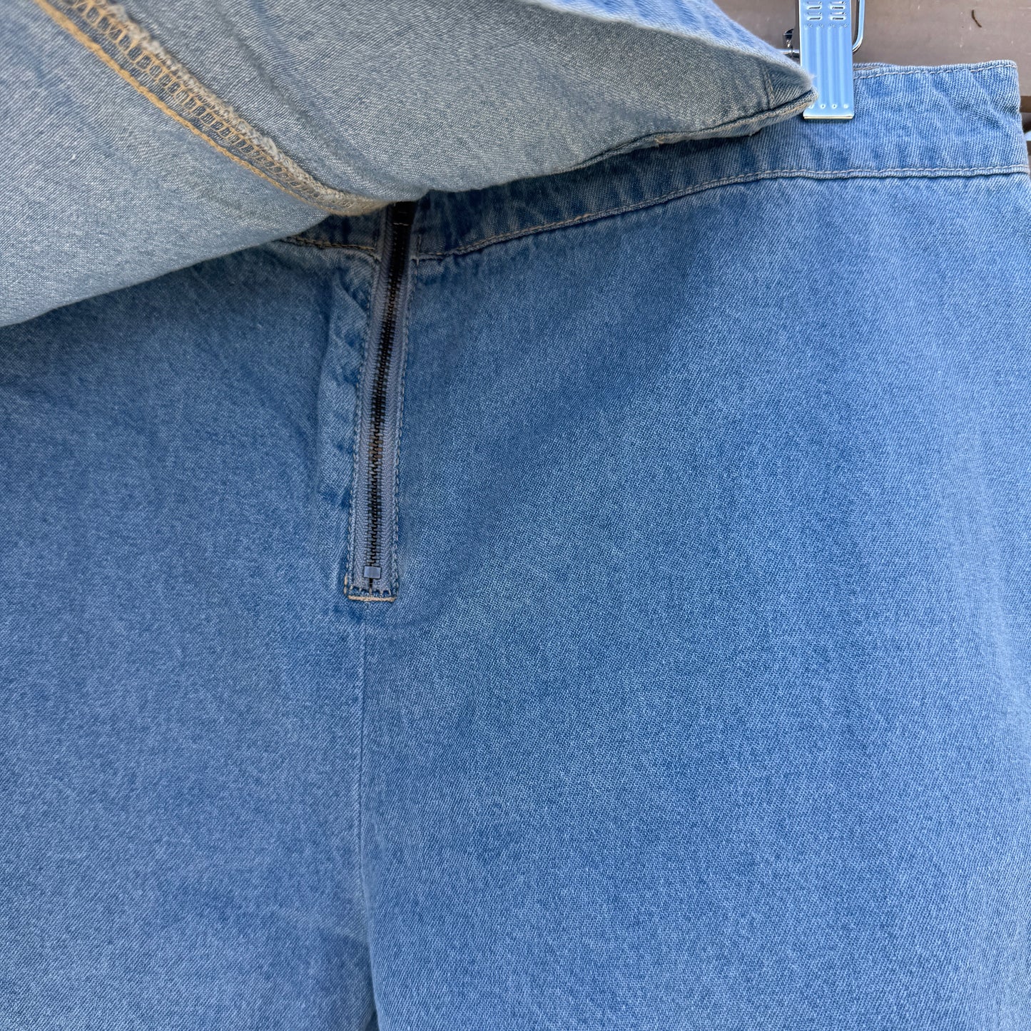Close-up of blue denim shorts with a zipper on a wooden surface